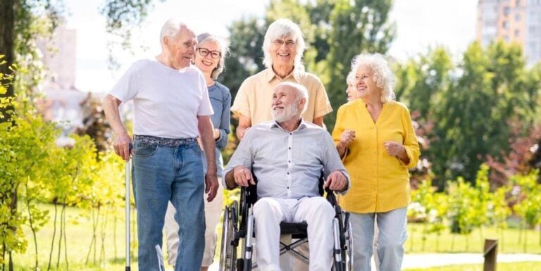 Elderly Group Walking Outdoors with Smiles at Memory Care Facility