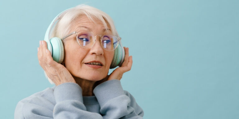 Elderly Woman Wearing Headphones on a Plain Background at a Memory Care Facility